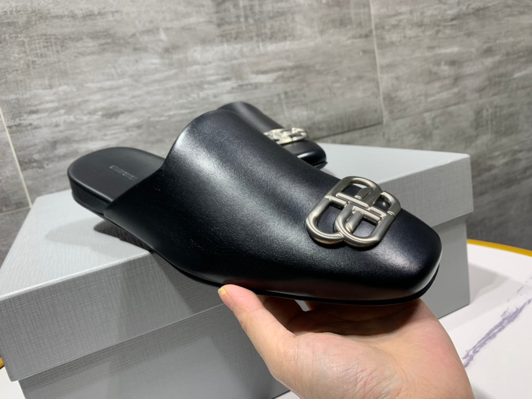Black leather slide sandal with curved silver buckle on the strap