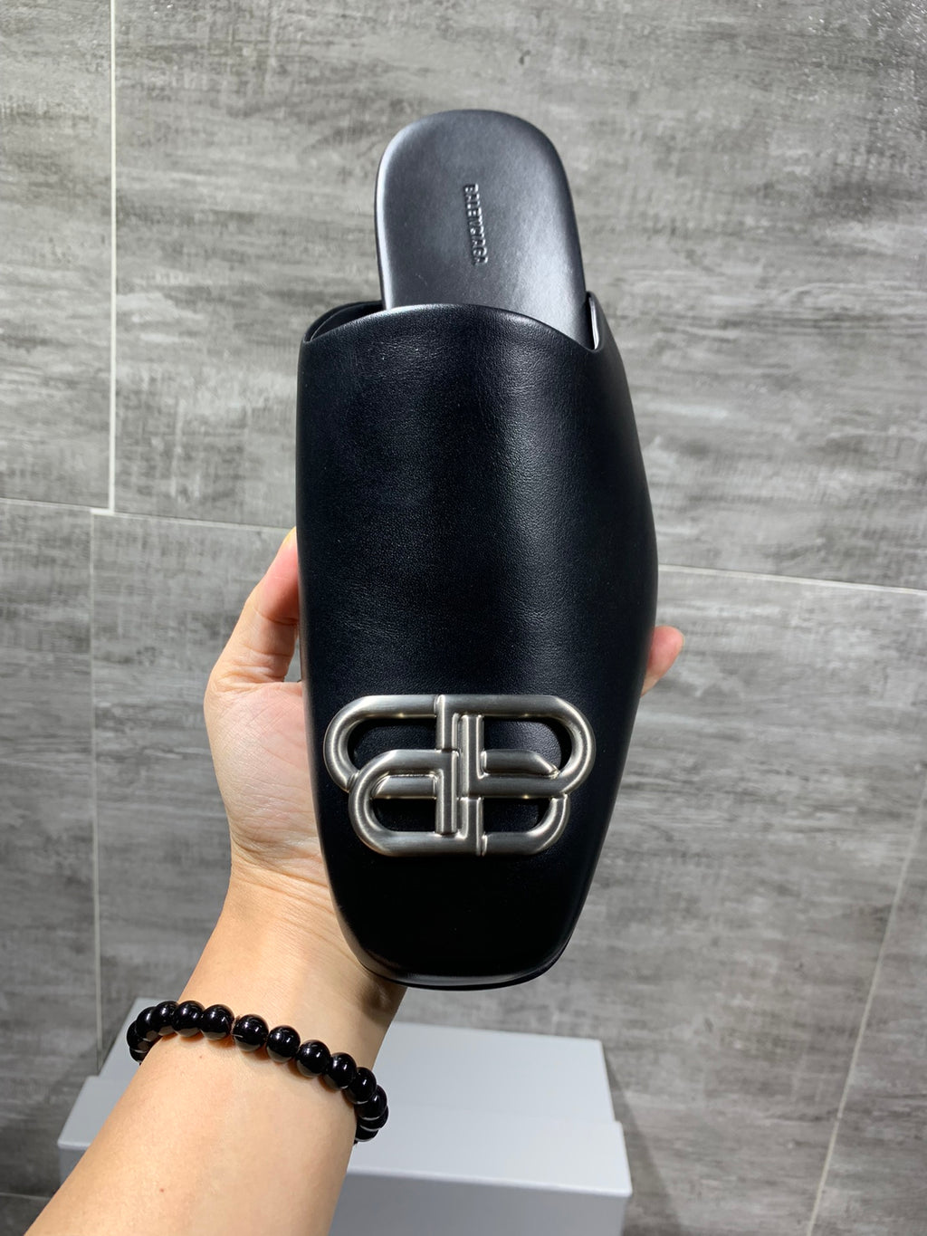 Black leather slide sandal back view with silver buckle hardware detail