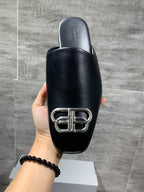 Black leather slide sandal back view with silver buckle hardware detail