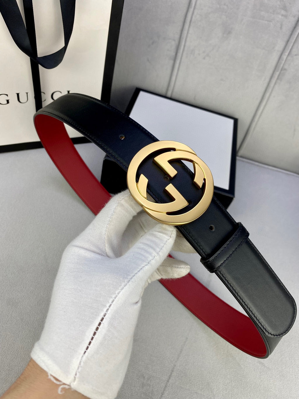 Black leather belt with gold-toned GG buckle and red underside