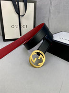 Black leather belt with gold-toned GG buckle and red strap lining