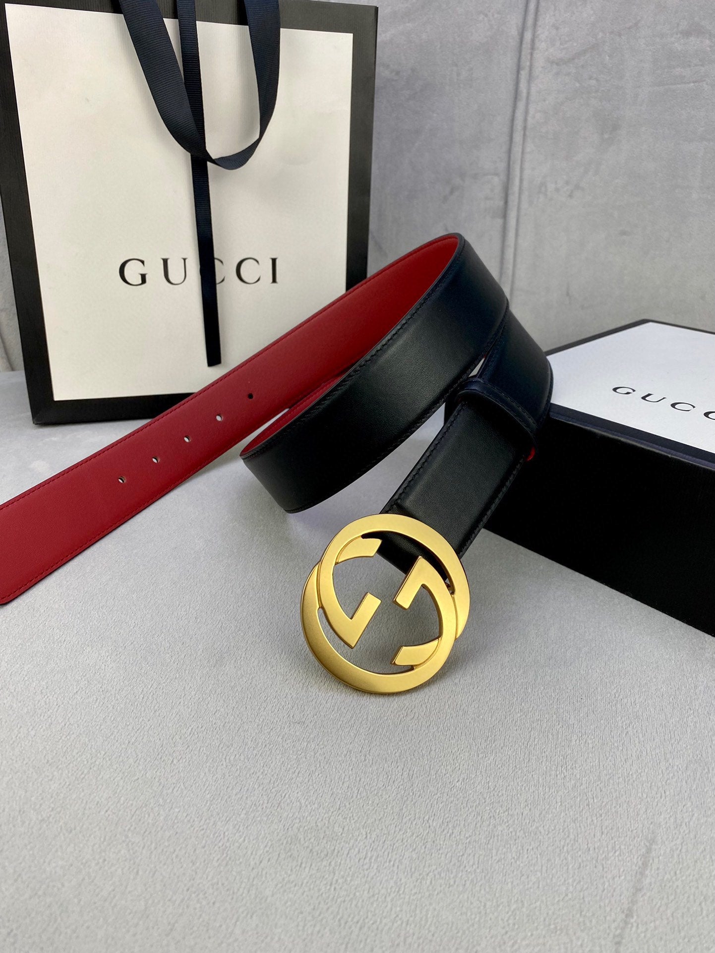 Black leather belt with gold-toned GG buckle and red strap lining