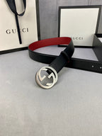 Black leather belt with silver GG buckle, red underside peeking, laid on display