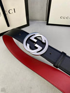 Dark leather belt with silver GG buckle and red underside, angled view on display