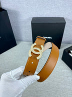 Tan leather belt close-up with rhinestone CC buckle and round metal hole marks