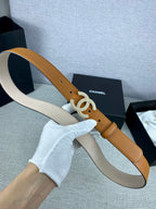Tan leather belt held by a hand, with rhinestone CC buckle and adjustment holes