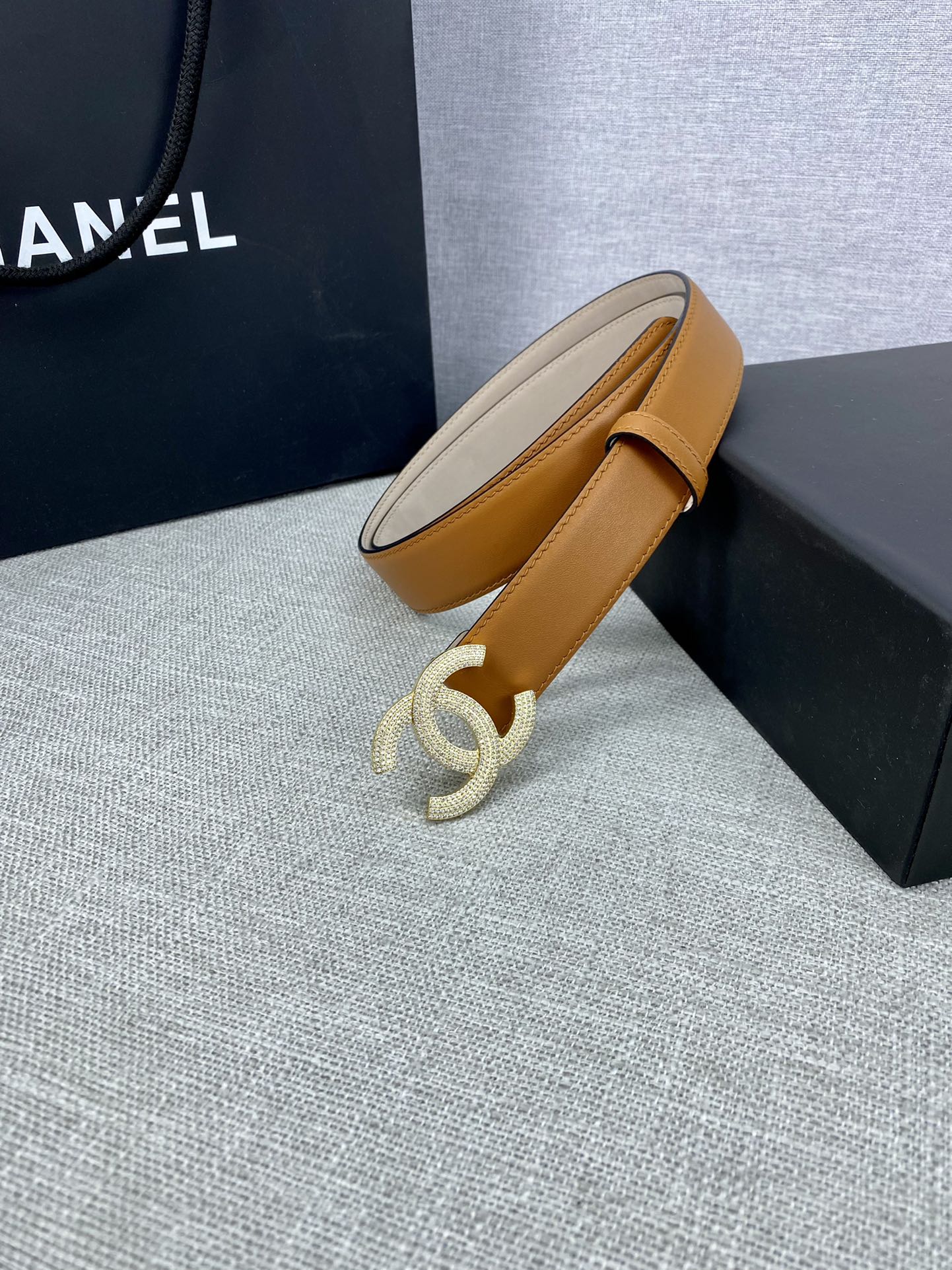 Tan leather belt end view with rhinestone CC buckle and stitched strap edge