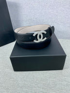 Black leather belt with silver-tone CC buckle on a dark box base