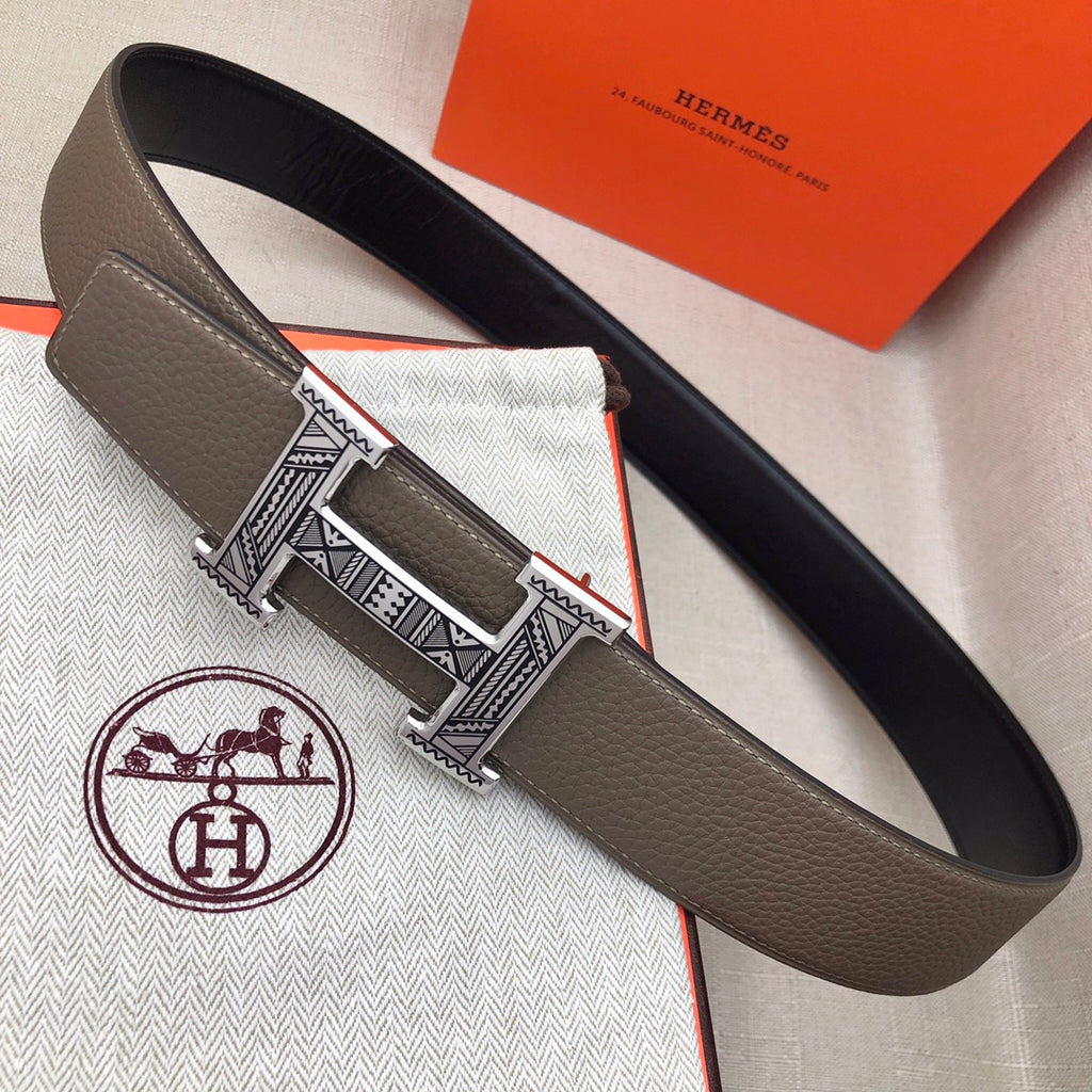 Taupe leather belt with wide silver-tone engraved buckle, laid flat
