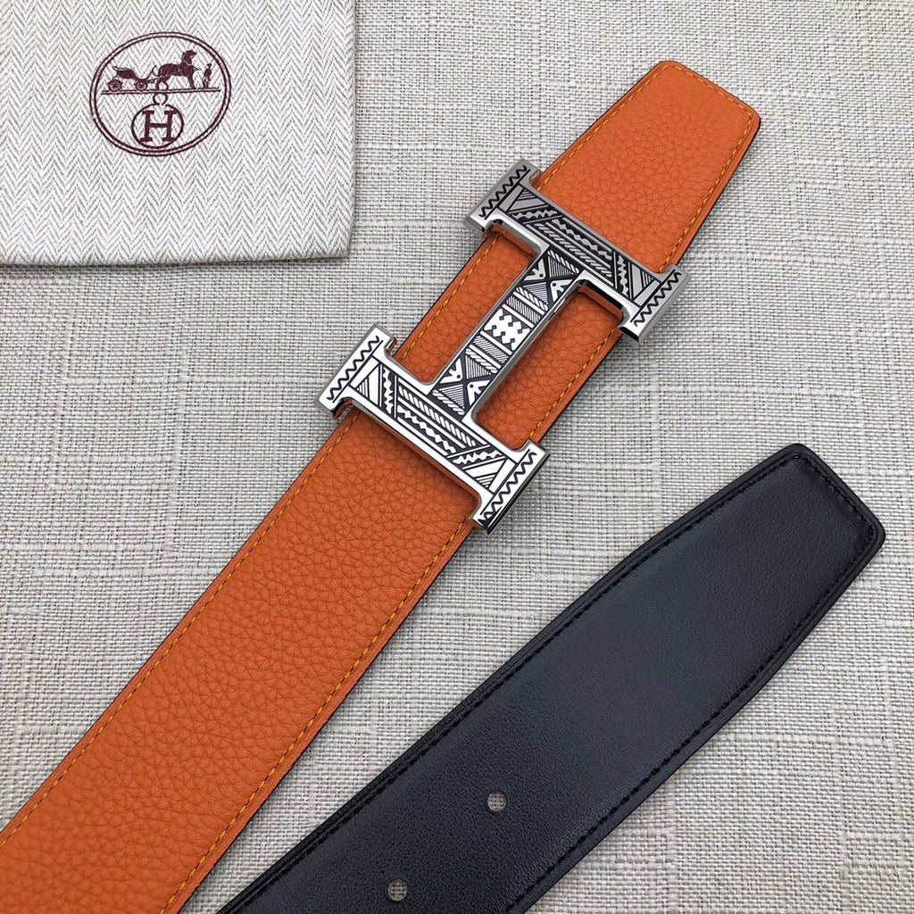 Hermes belt on fabric: orange strap with H buckle, plus dark strap beside it