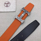 Hermes belt on fabric: orange strap with H buckle, plus dark strap beside it