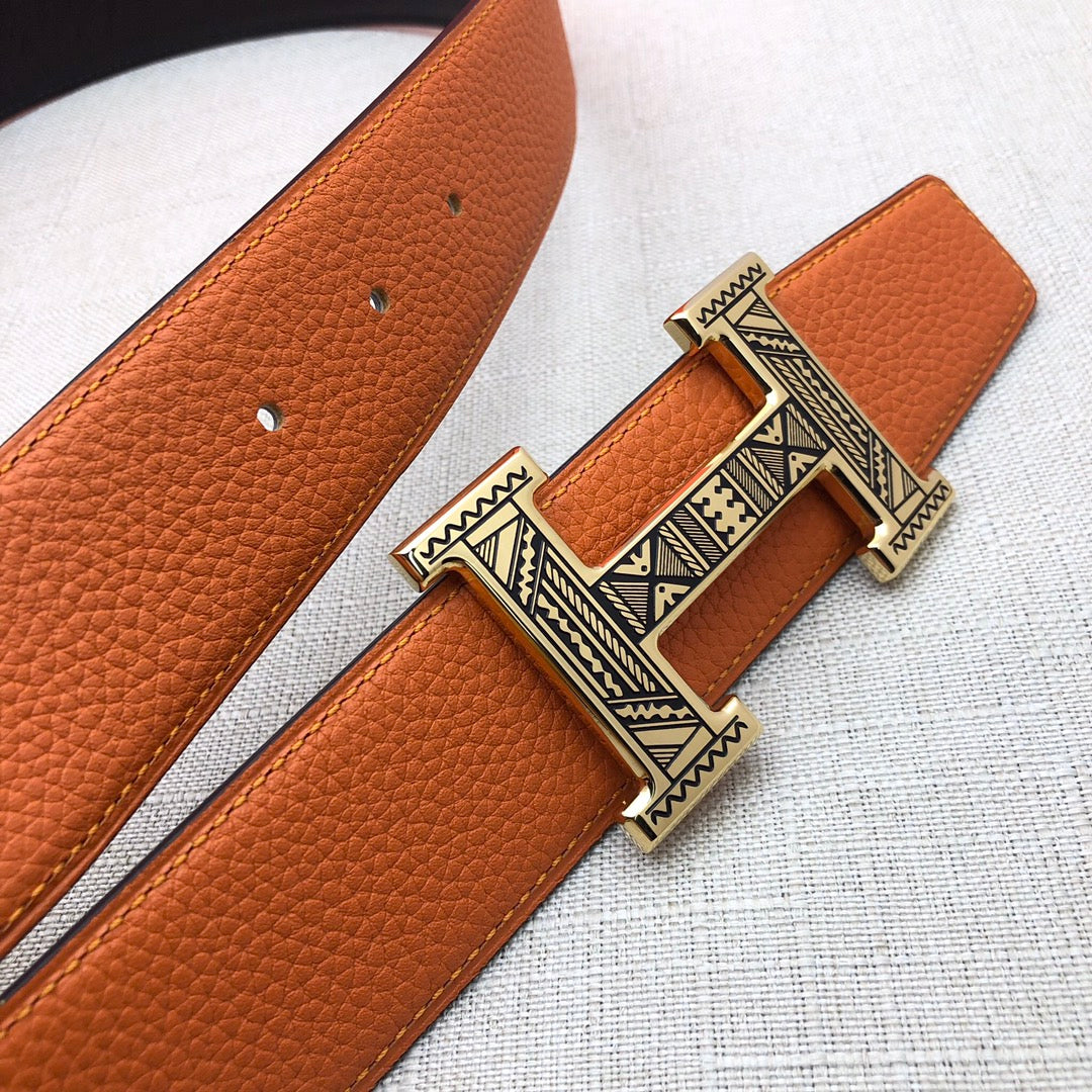 Hermes belt detail: orange textured leather with ornate H buckle and gold-tone hardware