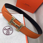 Hermes belt with orange textured leather strap and gold-tone H buckle on black backing