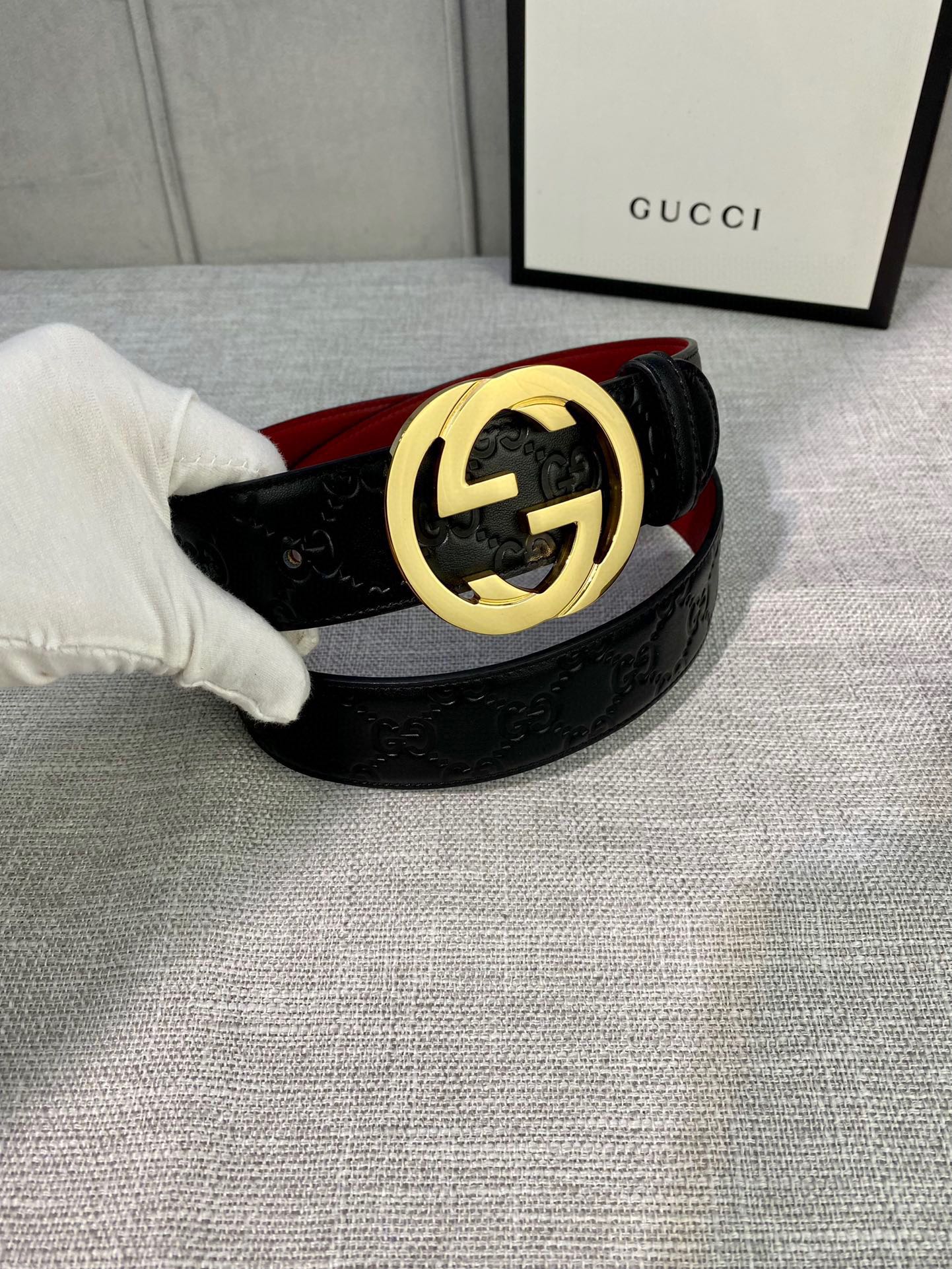 Gucci belt with black embossed leather and gold-tone GG buckle, red underside