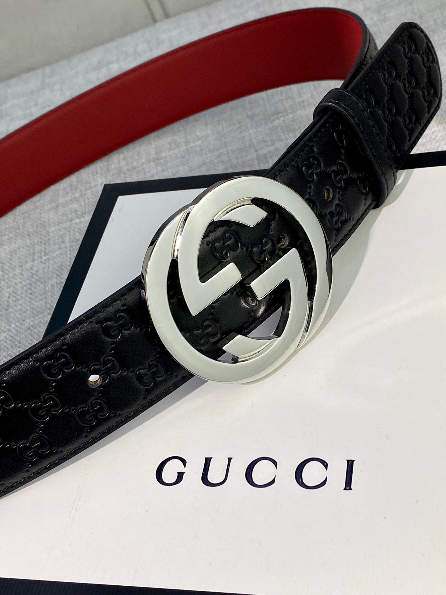 Gucci black leather belt with textured pattern and silver double-G buckle close-up