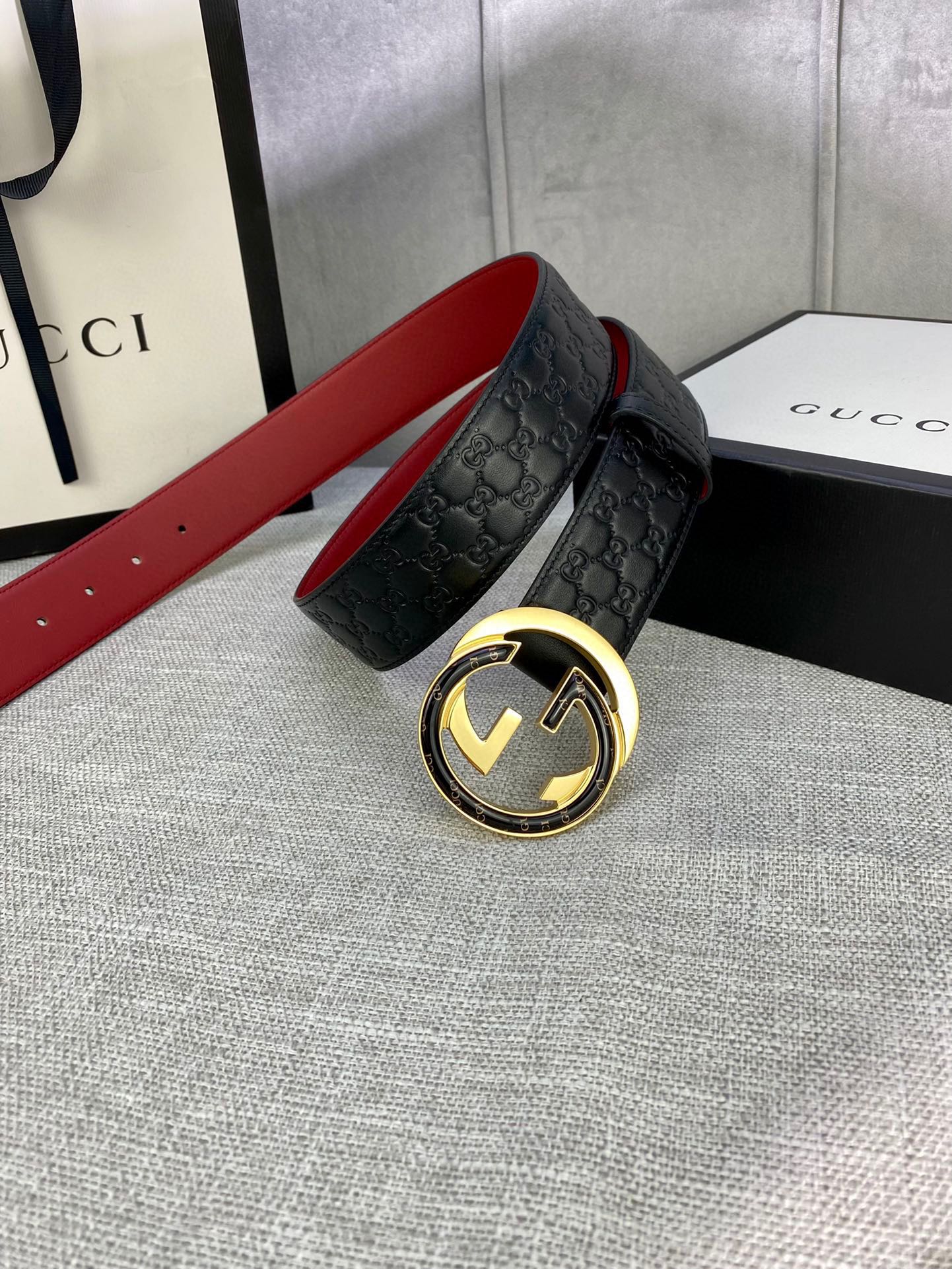 Gucci belt on display: black embossed strap with gold double-G buckle and red lining