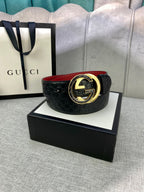 Gucci belt with black textured leather, gold buckle center, and red underside