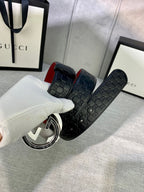 Gucci belt detail held in hand: black GG leather with red underside and silver buckle