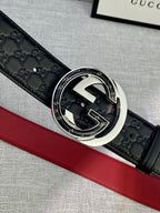 Gucci belt detail: black embossed leather with ornate silver buckle over red lining