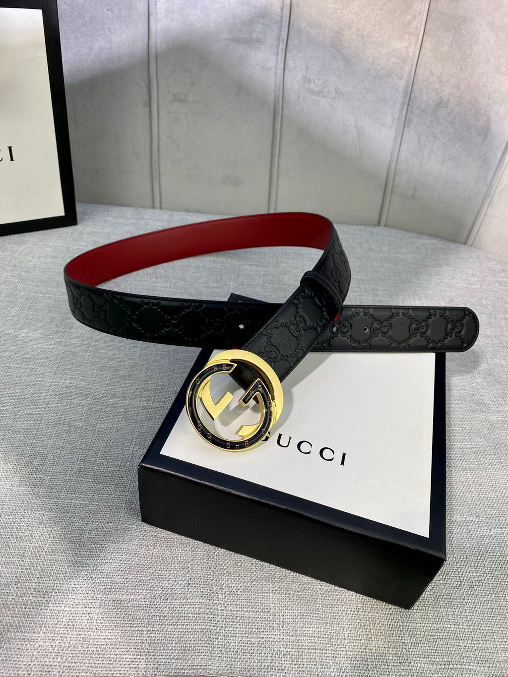Black Gucci-logo belt with round gold-tone buckle on gift box