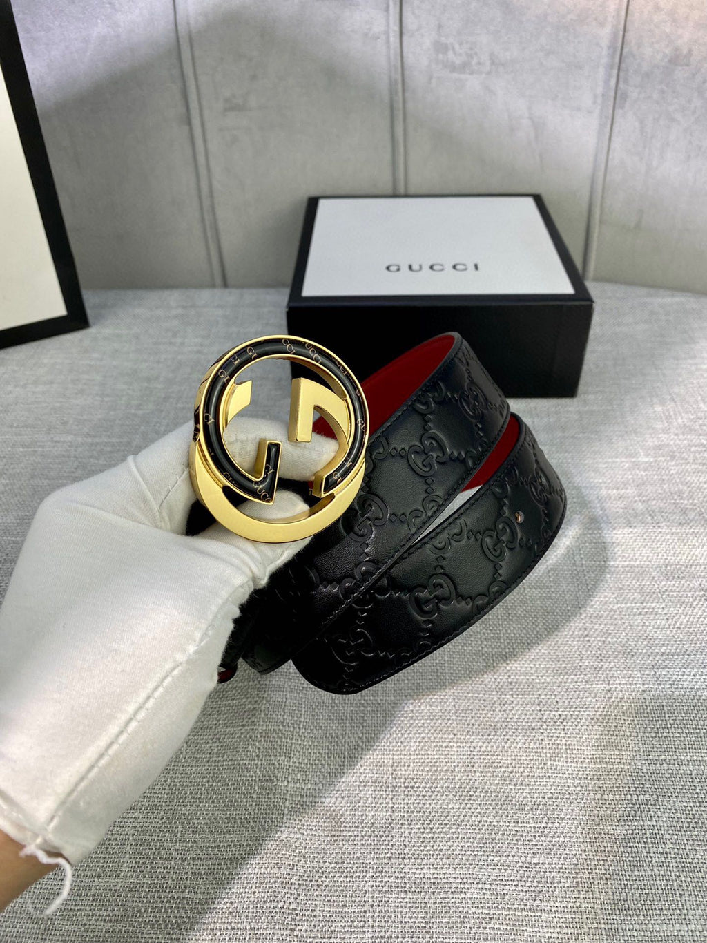Black Gucci-logo belt with gold-tone circular buckle and embossed strap
