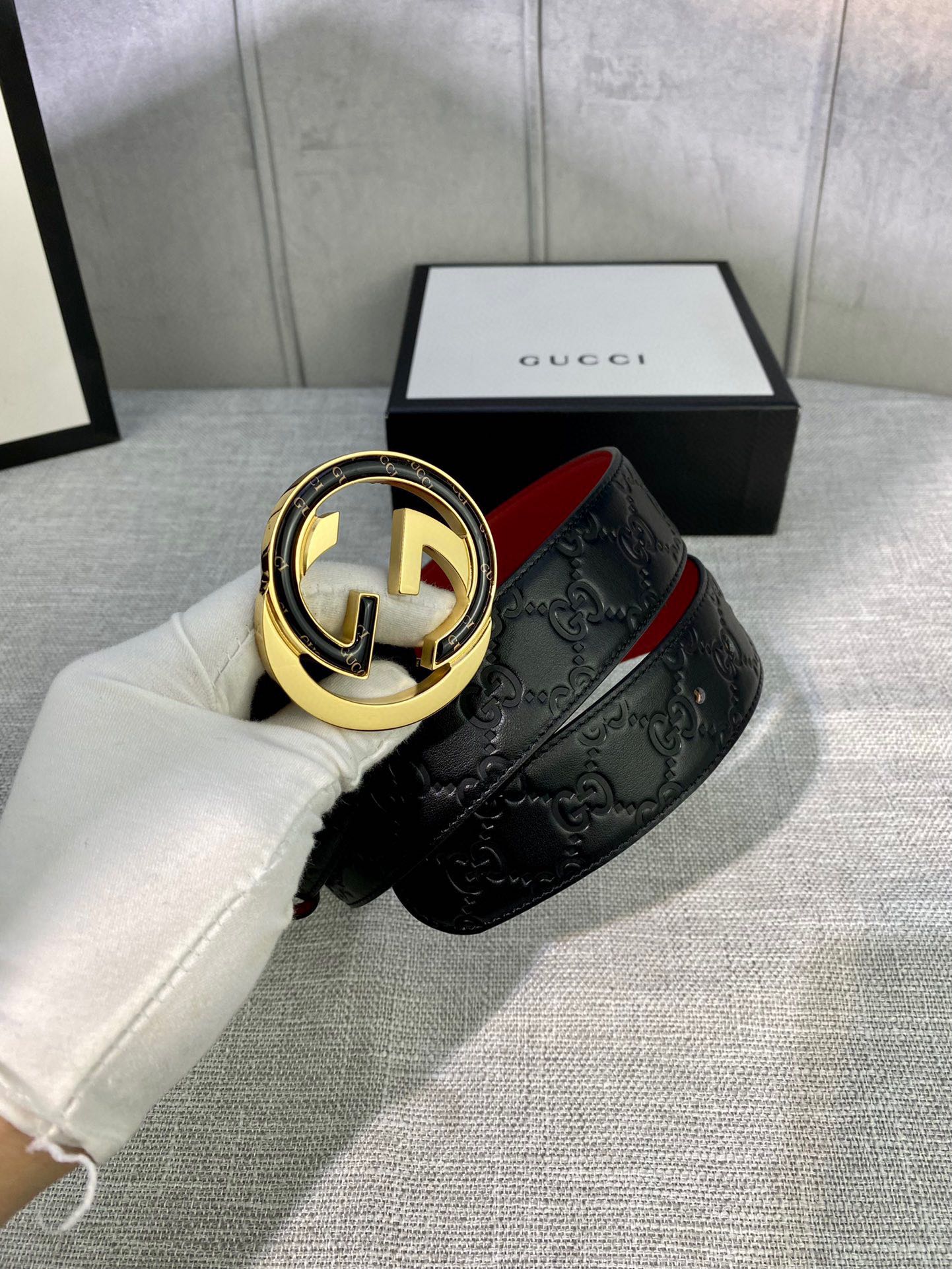 Black Gucci-logo belt with gold-tone circular buckle and embossed strap