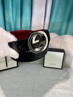 Black leather Gucci-logo belt with round silver-tone buckle while held by hand