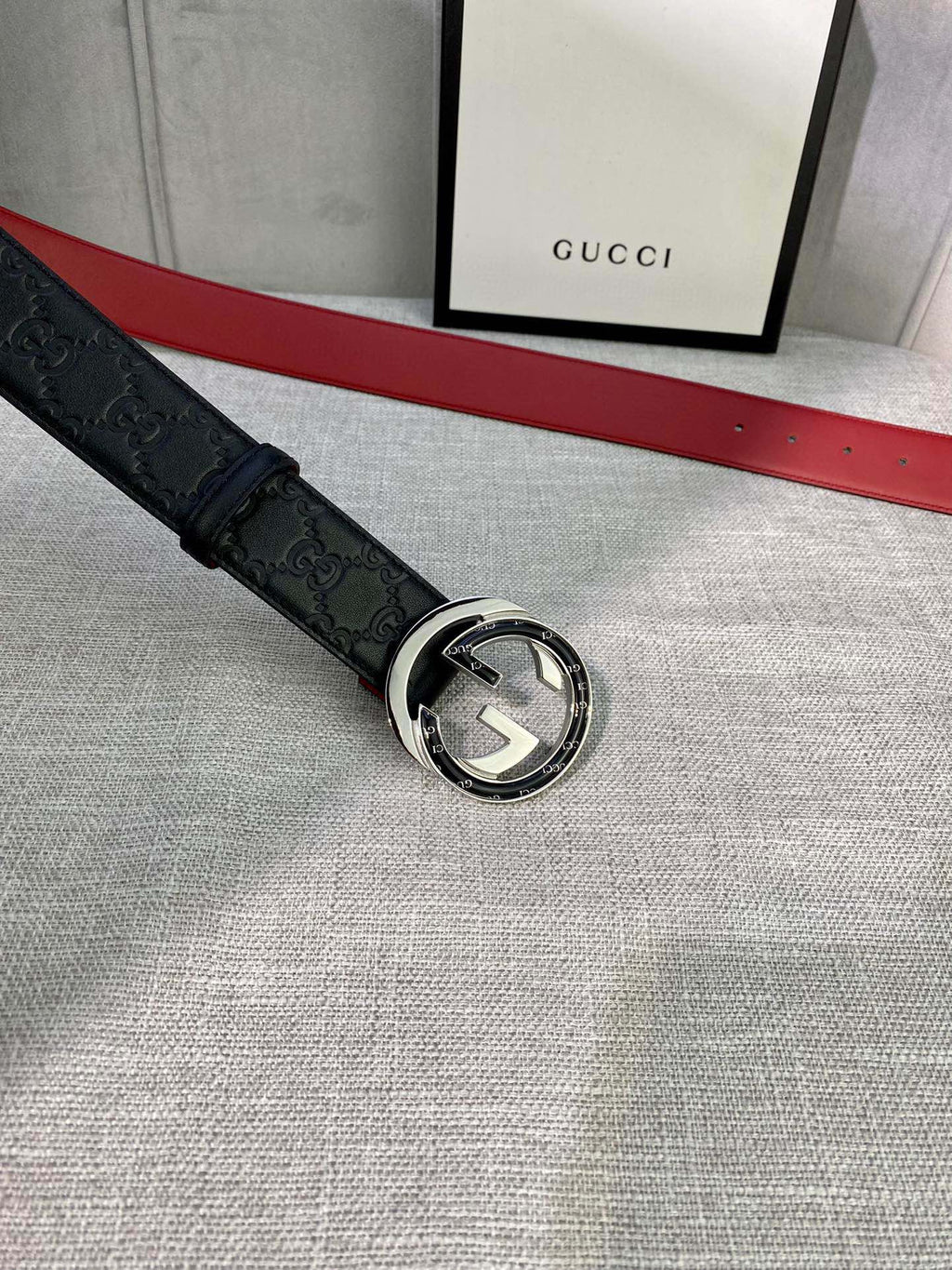 Black Gucci-logo belt with circular silver-tone buckle and embossed pattern