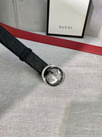 Black Gucci-logo belt with circular silver-tone buckle and embossed pattern