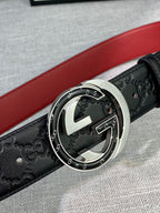 Black Gucci-logo belt close-up with round silver-tone buckle and red lining