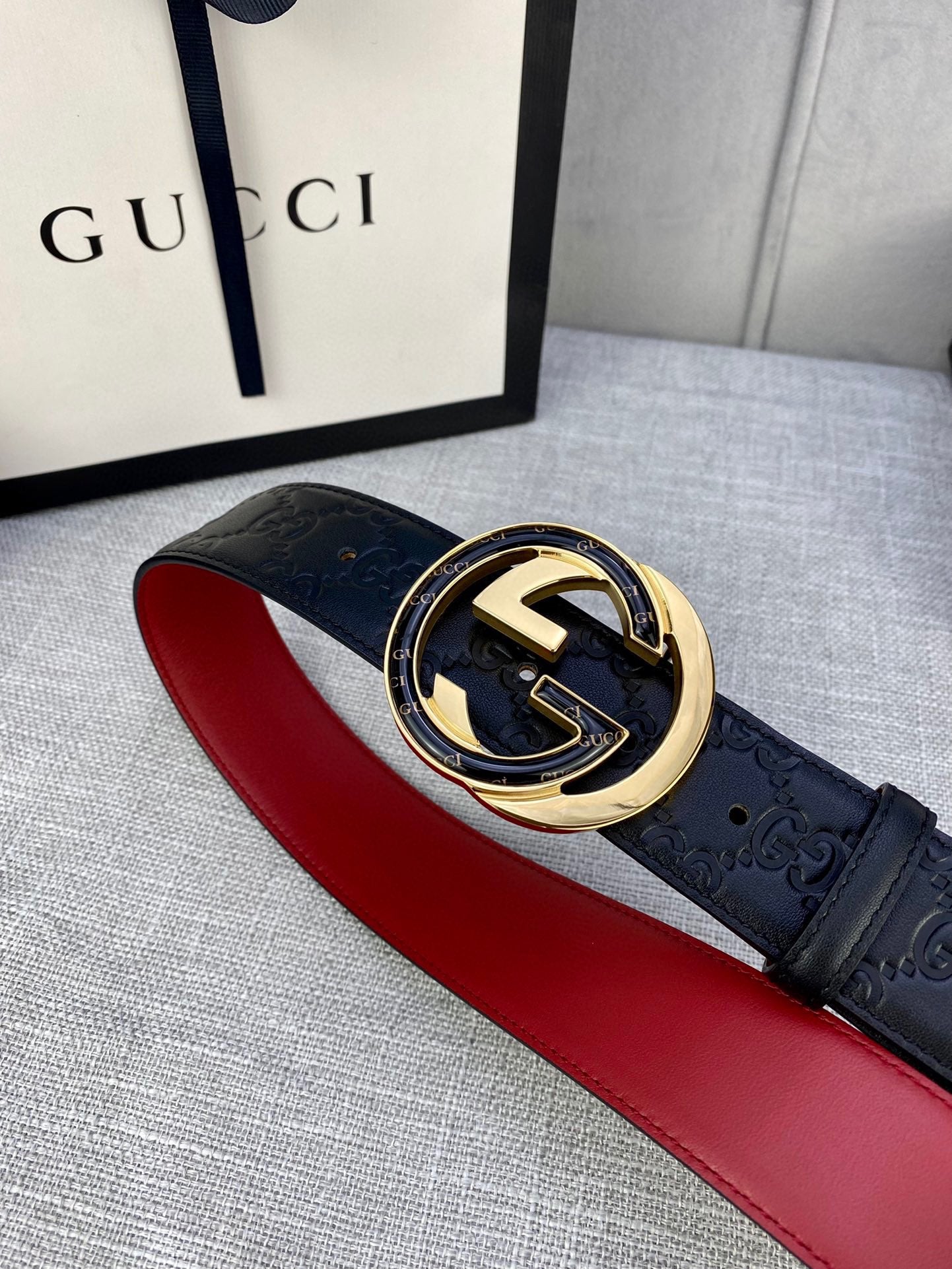Black Gucci-logo belt with gold-tone buckle on red strap lining