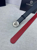 Versace leather belt laid flat: round gold Medusa-style buckle on dark blue strap with holes