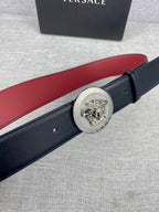 Versace leather belt close-up: round gold Medusa-style buckle on dark strap with red lining
