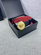 Versace leather belt in open box: dark strap with red underside and gold Medusa-style buckle
