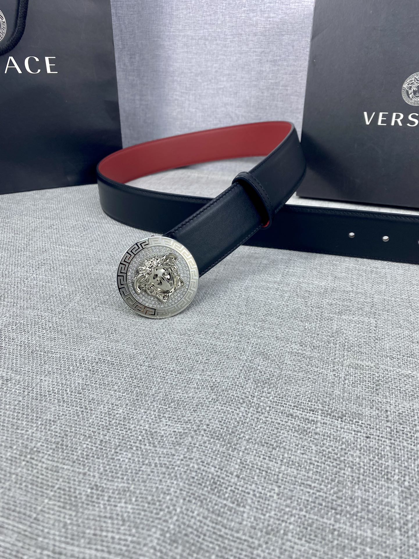 Versace leather belt with round gold Medusa-style buckle and dark strap, red underside