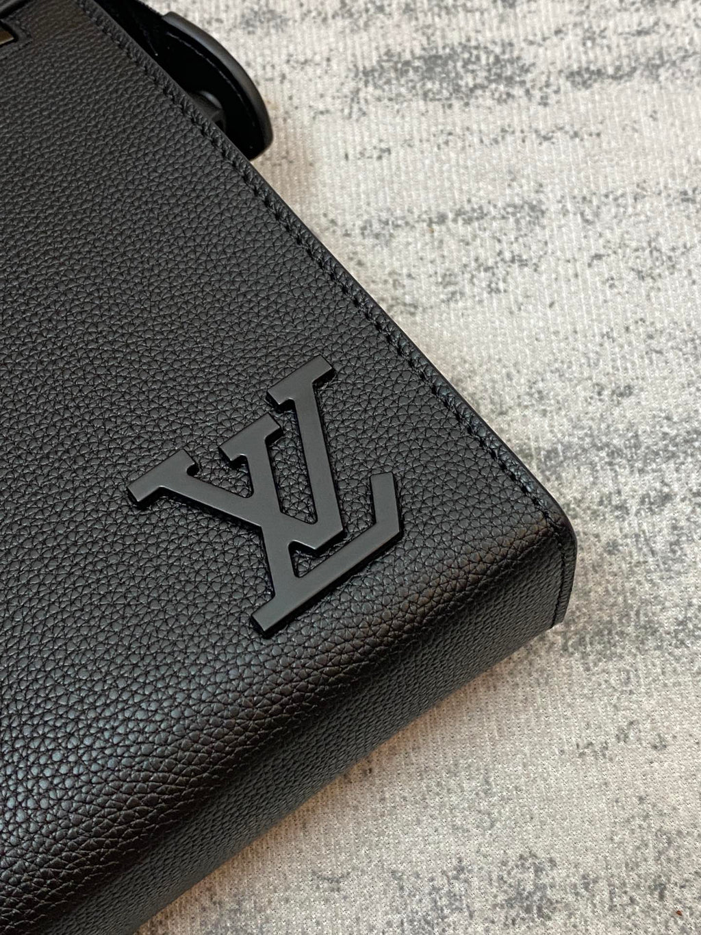 Louis Vuitton embossed logo on black textured leather corner