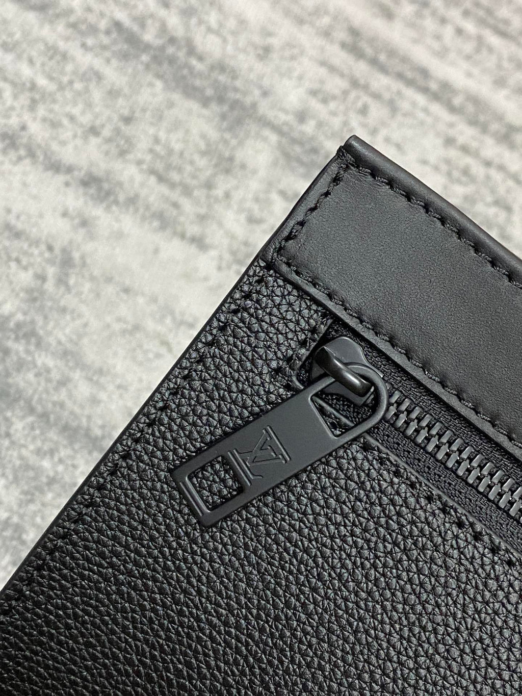 Louis Vuitton zip pocket detail, black textured leather with metal pull and trim