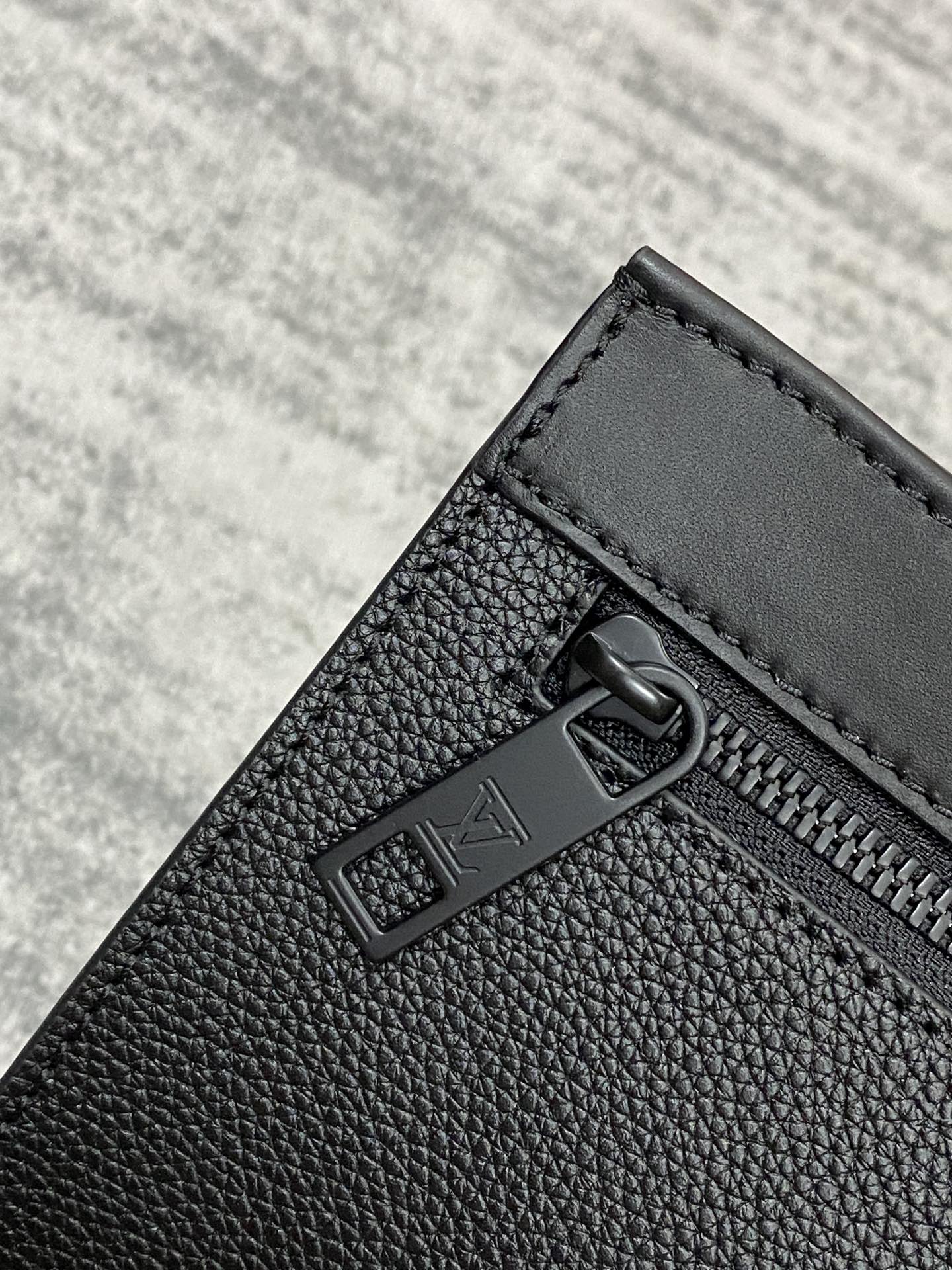 Louis Vuitton zip pocket detail, black textured leather with metal pull and trim
