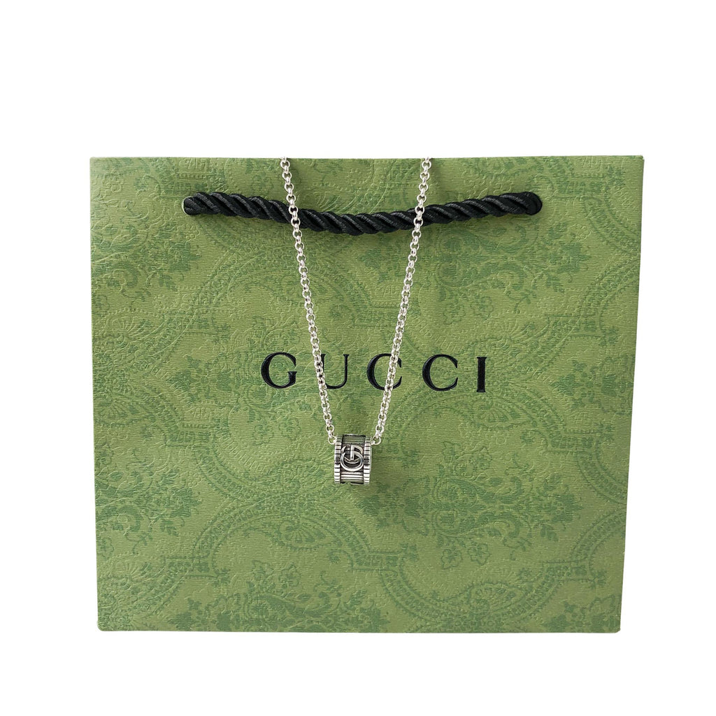 Gucci necklace on green gift bag, silver chain and logo pendant