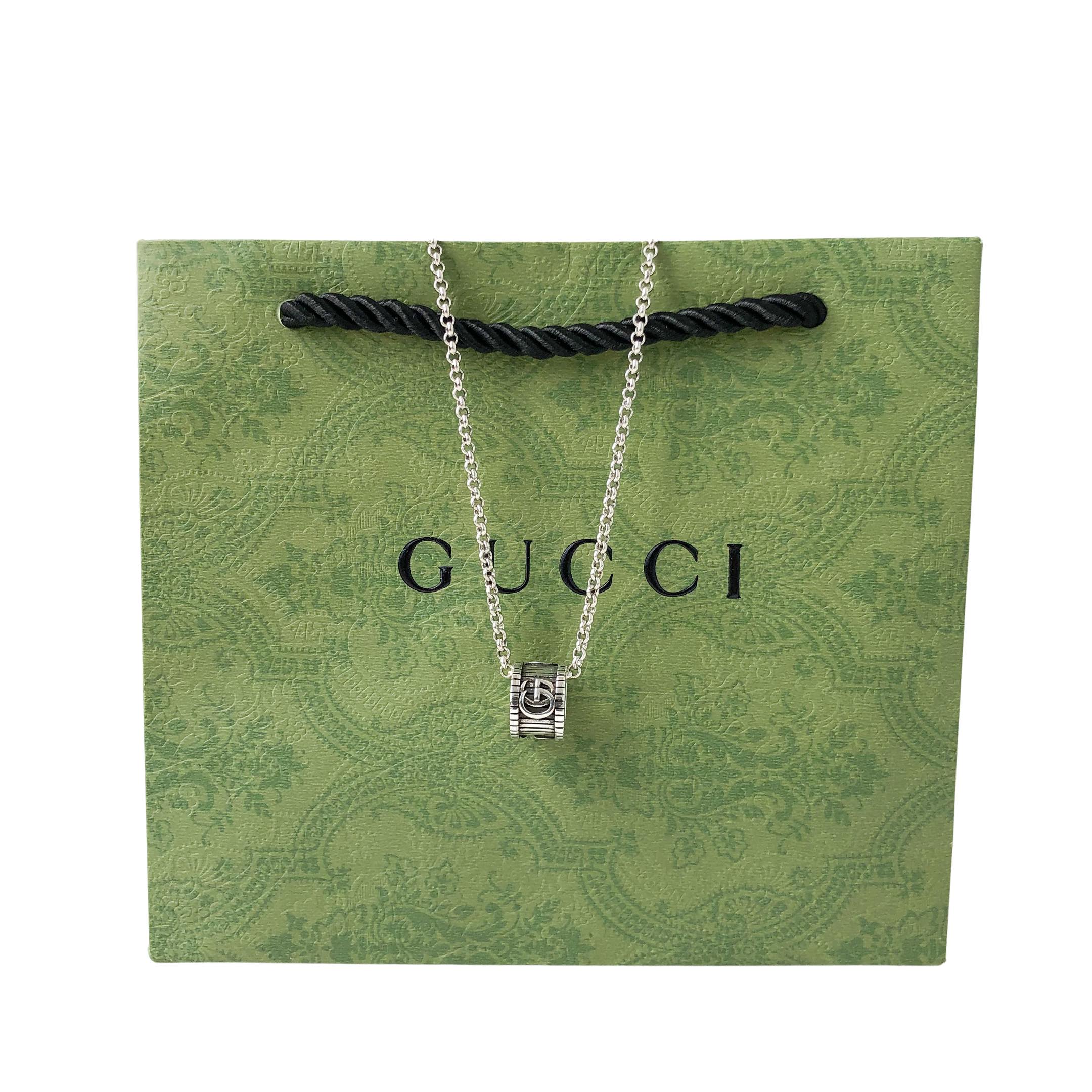 Gucci necklace on green gift bag, silver chain and logo pendant