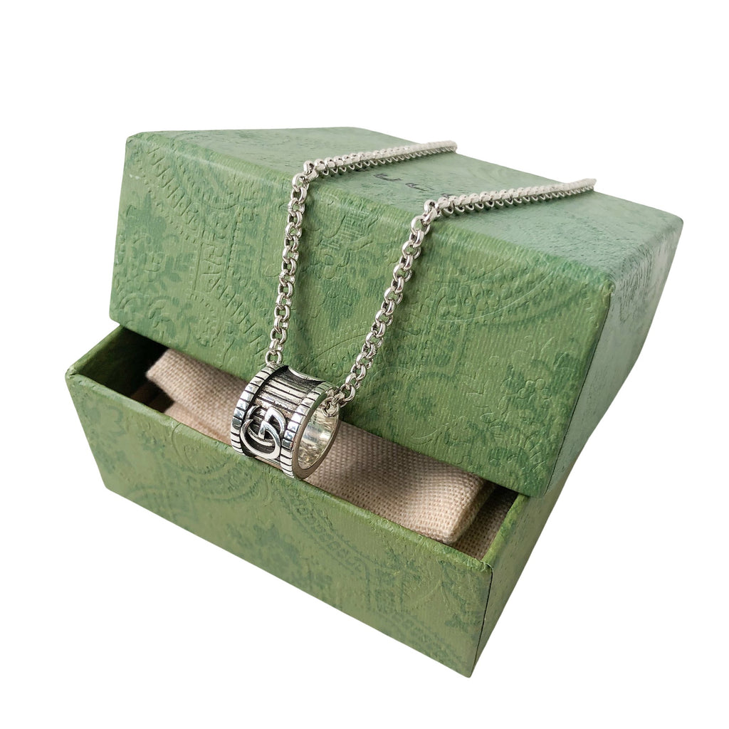 Gucci necklace on open green gift box, silver chain and logo pendant