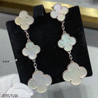 Silver clover dangle earrings with linked four-leaf motifs and pale inlay accents.