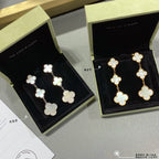 Clover dangle earrings in gold and silver with linked four-leaf motifs, shown in boxes.
