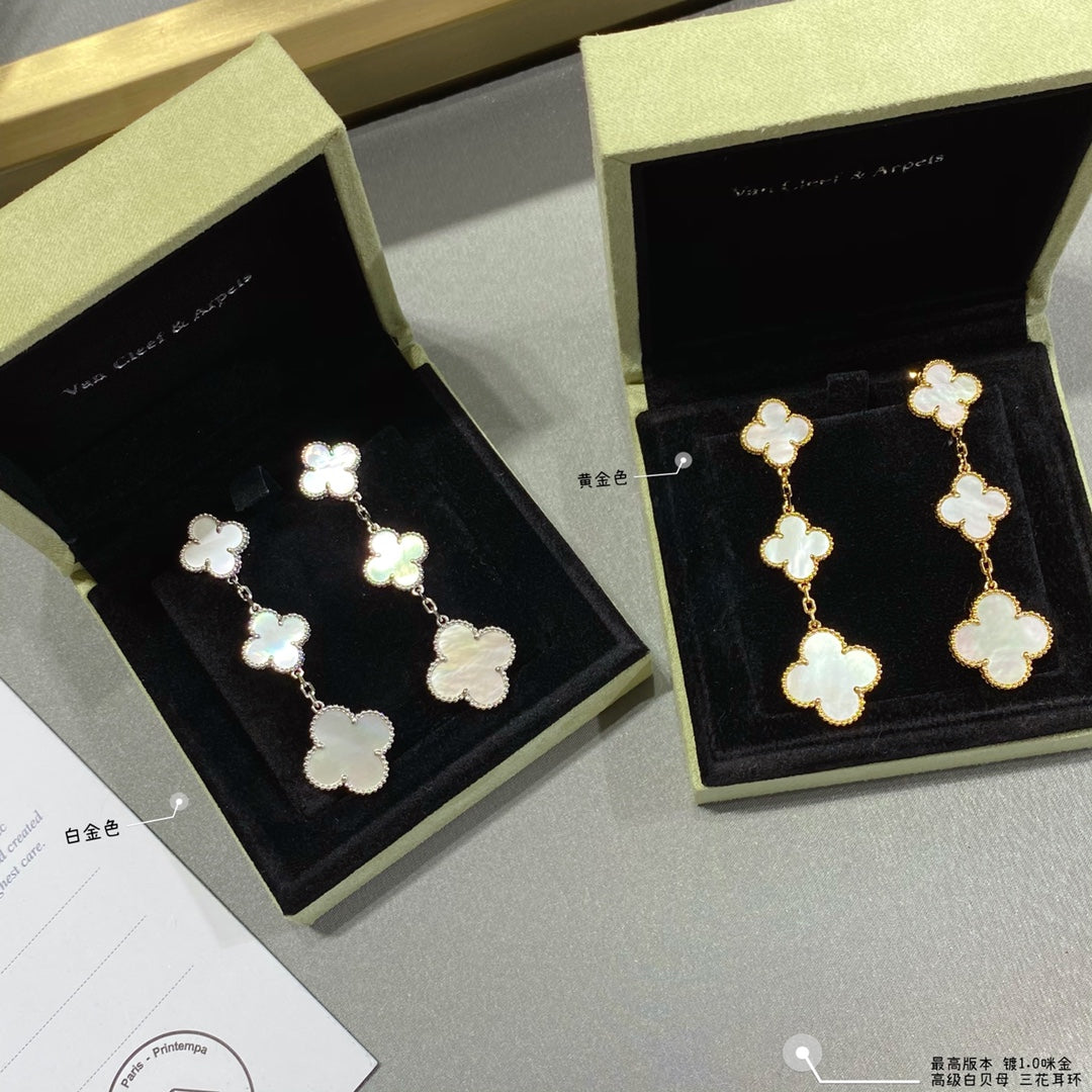 Clover dangle earrings in gold and silver with linked four-leaf motifs, shown in boxes.