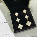 Gold clover dangle earrings with three linked four-leaf motifs and pale inlay accents.