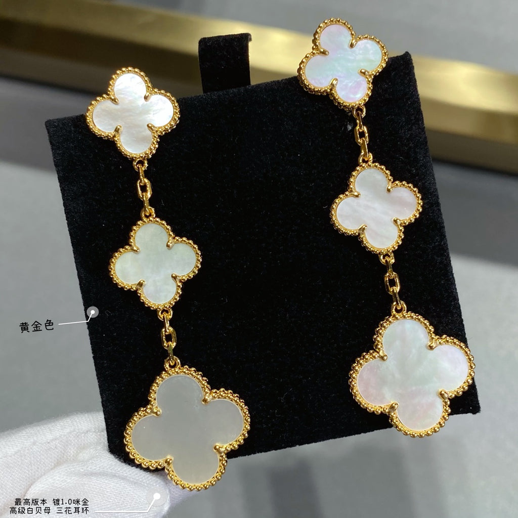 Gold clover drop earrings with linked four-leaf motifs and pale inlay stones.