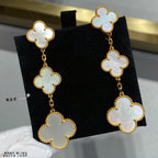 Gold clover drop earrings with linked four-leaf motifs and pale inlay stones.
