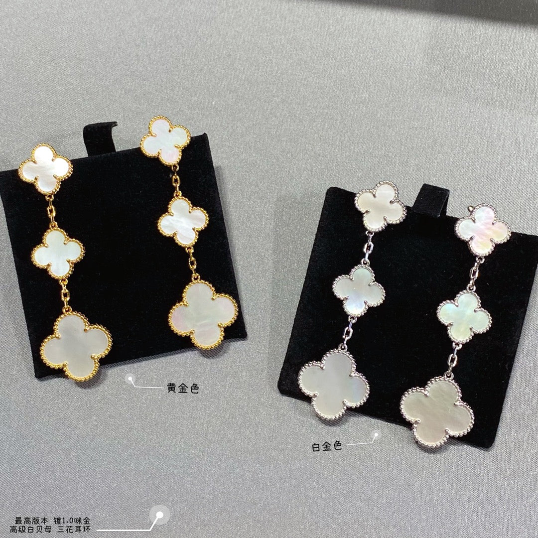 Clover dangle earrings in gold and silver, each with linked four-leaf motifs.