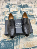 Prada unisex lace-up dress shoes, dark leather, perforated toe and wing tip.