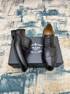 Prada unisex lace-up oxford shoes, dark leather with brogue perforations, side view